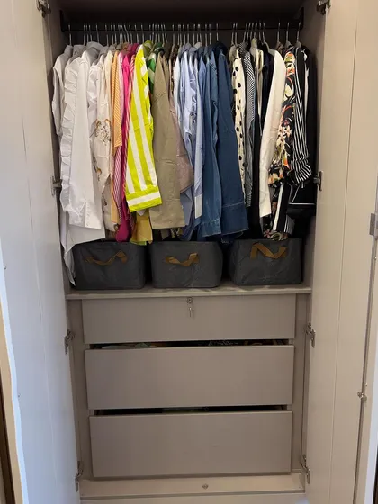 This compact wardrobe uses baskets on shelves above the hanging rod to maximize vertical space, a great solution for smaller closets.