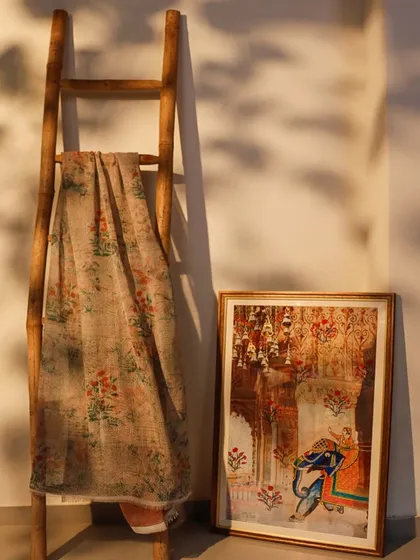 Framing beauty, draping warmth. This vignette showcases how our art and textiles can work together. A framed piece of traditional Indian art is paired with a draped length of our printed fabric, creating a beautiful, textural story.