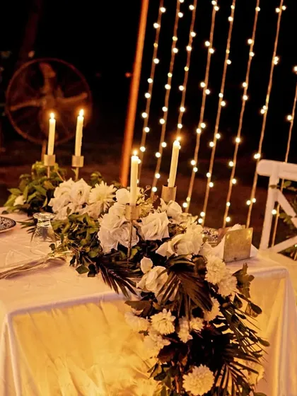 The celebration continues with a private dinner for two. I set up this elegant table with a lush floral runner, classic candlesticks, and a backdrop of cascading fairy lights, ensuring the romance lasts long after the "yes."