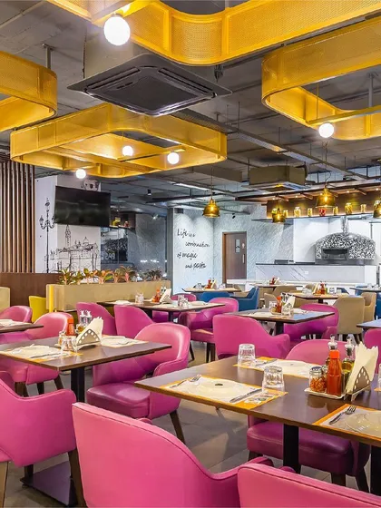 A vibrant dining section at Pasta Street, where bold pink chairs create a striking contrast against the custom yellow ceiling fixtures. This area was designed to be energetic and memorable, reflecting the lively spirit of the Italian street food concept.