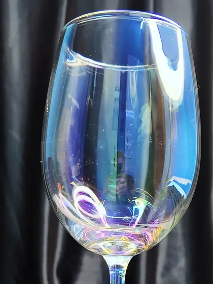 An iridescent wine glass that adds a unique, colorful shimmer to your table setting. It's a great way to make your event's bar service stand out.