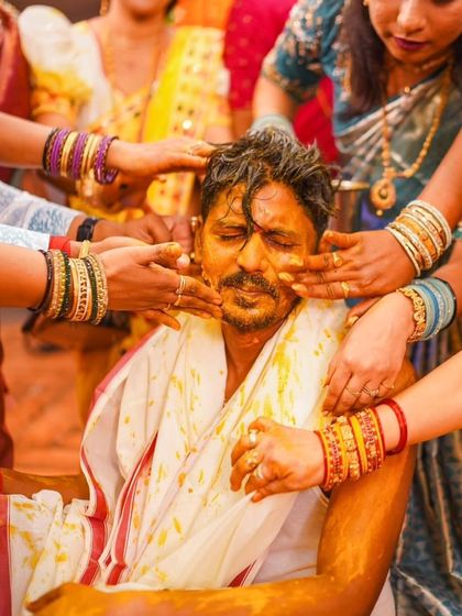 A touching moment as a family member applies Haldi to the groom. These candid shots capture the love and blessings that surround the couple.