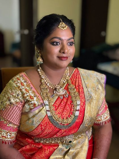 The final look for Dr. Preetha's muhurtham. Her smokey gold eyes, coral red lips, and radiant skin came together for a stunning traditional bridal look.
