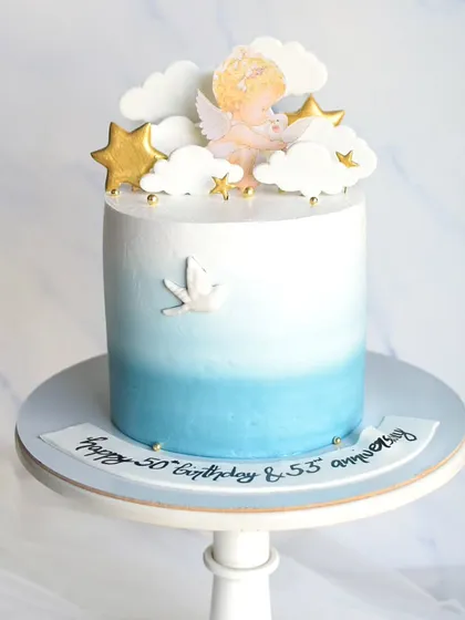 A memorial cake to celebrate the lives of loved ones. The blue ombre design represents the sky, decorated with clouds, stars, and a dove, creating a peaceful and loving tribute.