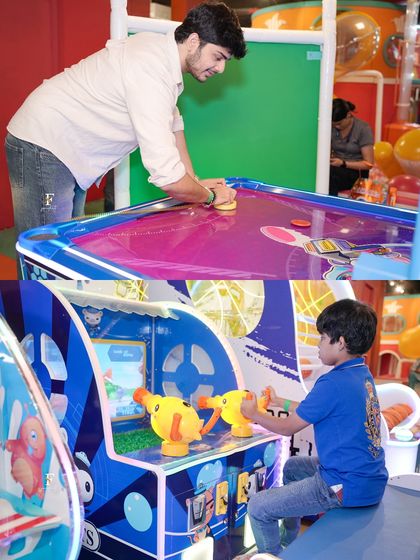 A father and son enjoying the arcade together. We love creating opportunities for families to bond over shared activities like air hockey and shooting games.