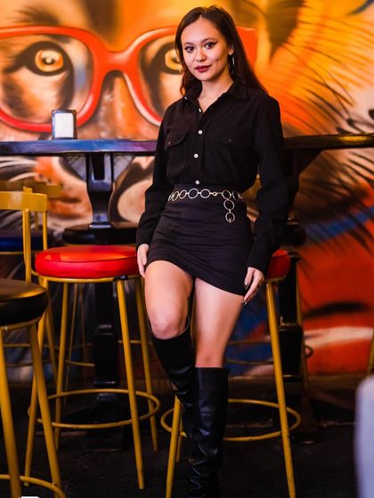 A guest posing in a black dress and boots.