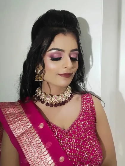 The half-up hairstyle with soft waves complements the heavy embroidery of her sangeet outfit perfectly.