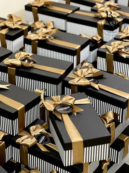 A large order of corporate gift hampers ready for dispatch. The striking black and white striped boxes are paired with solid black lids and finished with luxurious gold satin ribbons, creating a look of modern sophistication for client or employee appreciation.