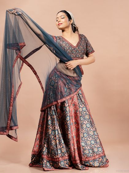 A full-length shot of the model in the printed lehenga, playfully holding the dupatta to showcase its flow and texture.