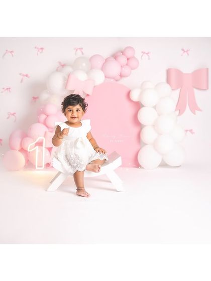 Pointing to the next adventure! This little girl is all smiles during her pink and white first birthday photoshoot.