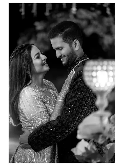 A beautiful black and white shot of the couple sharing a dance. The composition, with a light in the foreground, adds an artistic touch to this romantic moment.
