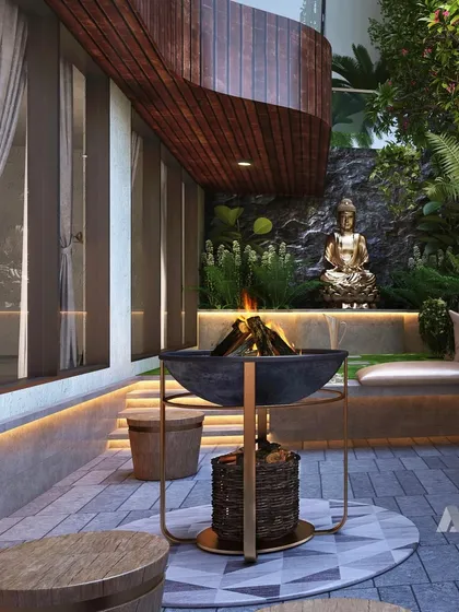 A detail of an outdoor patio at an Evara villa. This space is designed for serene relaxation, with a fire pit, comfortable seating, and a connection to the landscaped garden and a Buddha statue for tranquility.