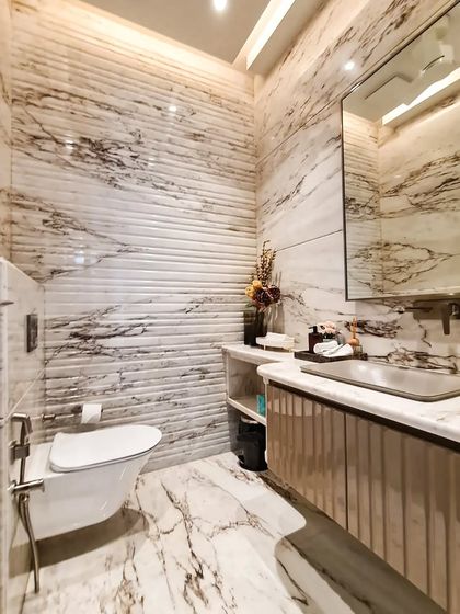 A powder room where texture and material take center stage. The fluted marble wall adds a layer of sculptural detail, complemented by the continuous veining of the marble floor and vanity.
