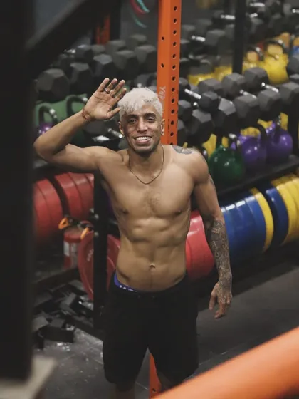 A wave and a smile, but the work is always there. Even in moments of rest, the fighter's physique shows the dedication that defines our team.