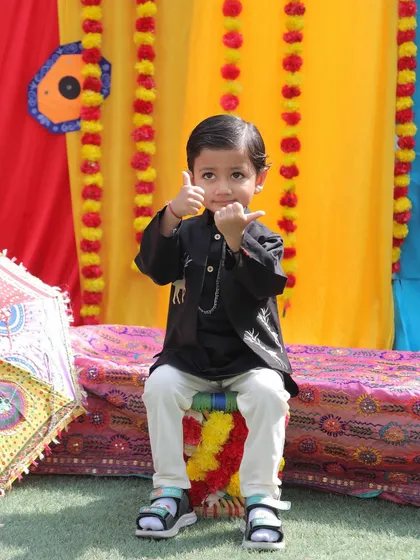 A thumbs-up for a fun Baisakhi celebration. This little boy in a black kurta is enjoying the festive decorations and cultural activities.