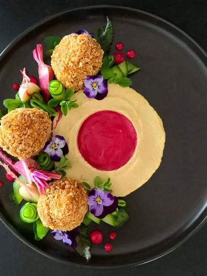 Plating is an art, and we make sure our appetizers look as incredible as they taste. Here, crispy fried croquettes are arranged with a colourful beetroot dip, edible flowers, and fresh greens.
