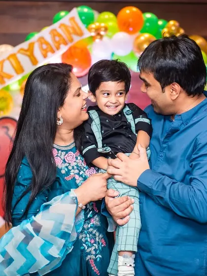 A candid family portrait filled with smiles at a second birthday party with a colorful animal theme.