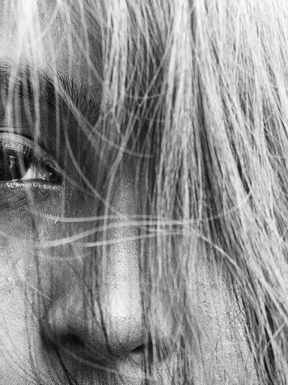 An extreme close-up in black and white, with hair blowing across the face. This shot is all about texture, emotion, and a sense of mystery.
