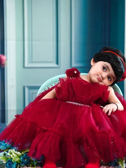 A little princess in a stunning red dress, looking elegant for her first birthday photoshoot.