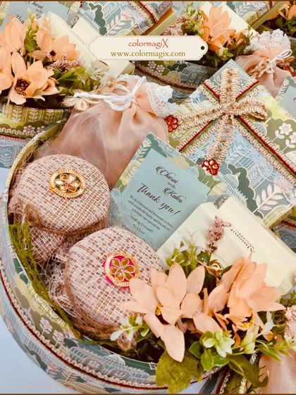 A beautifully curated wedding hamper in a round basket, featuring delicate floral arrangements and a personalized thank you card. This favor is perfect for expressing gratitude to your guests.