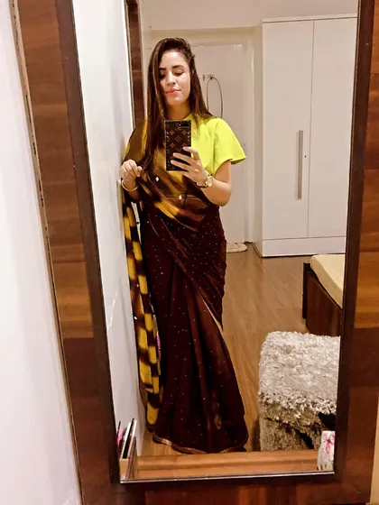 I love mixing colors and styles. Here, a traditional brown and yellow saree is paired with a modern, bright lime-green blouse with flutter sleeves for a unique and eye-catching combination.