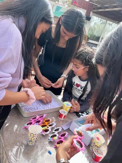 Party activities go beyond the paintbrush. Here, kids are having a blast decorating their own funky sunglasses, adding another layer of creative fun to the celebration.