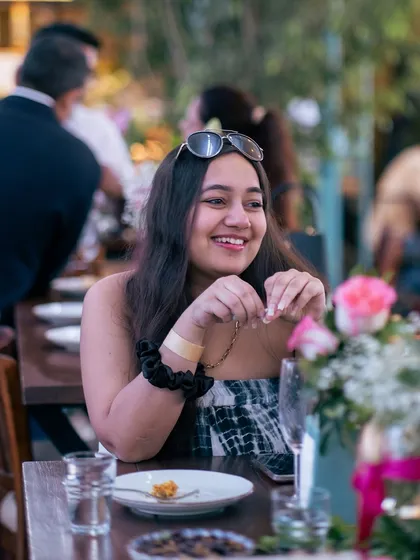 A guest's happy expression as she enjoys her meal, surrounded by flowers and friends.