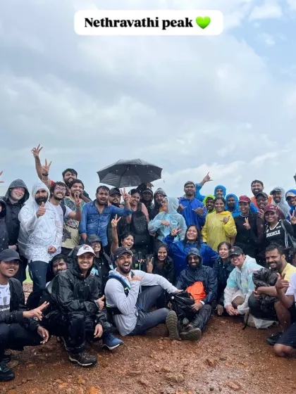 A large, cheerful group at the Nethravathi peak, celebrating their successful climb together in the rain.