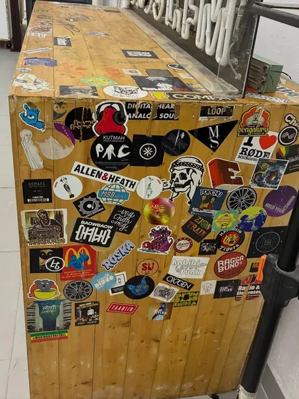 The top of the DJ booth, covered in stickers from artists and friends who have passed through our doors. It's a physical record of our community and journey.