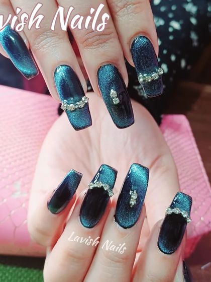 Deep teal cat-eye nails in a coffin shape, embellished with elegant rhinestone bands for a touch of luxury.