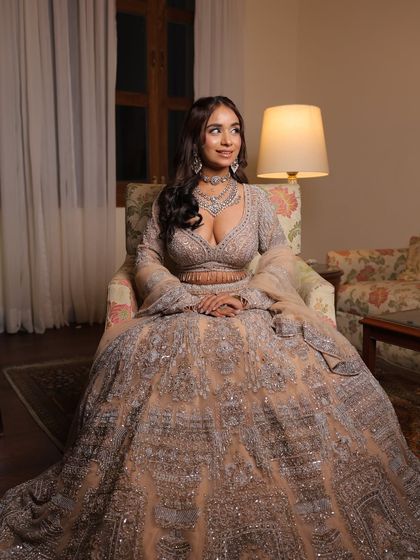 A full-length seated shot of the silver-grey engagement lehenga. The voluminous skirt and detailed embroidery create a look of pure elegance.