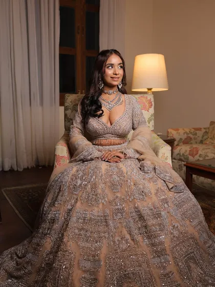 A full-length seated shot of the silver-grey engagement lehenga. The voluminous skirt and detailed embroidery create a look of pure elegance.