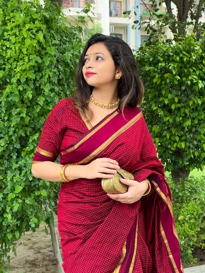A close-up shot, focusing on the texture of the saree and the delicate temple jewelry necklace.