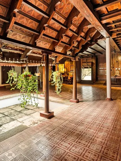 Another perspective of the Aranmula Palace's inner courtyard, highlighting the hanging plants and the interplay of light and shadow. This architectural design promotes natural ventilation and a connection to the elements.