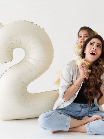 A sweet and candid moment from a second birthday shoot. The little girl gets a piggyback ride from her mom, both sharing a happy, upward gaze.