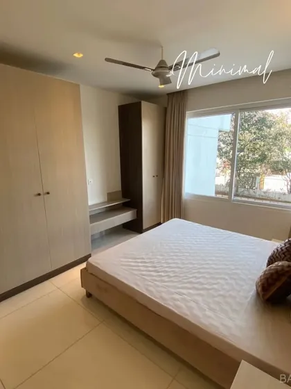 This bedroom showcases a minimal aesthetic with light wood-finish wardrobes and a simple, clean layout that maximizes space and natural light.