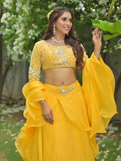 The model interacts with the surrounding nature, showing how this bright yellow outfit stands out beautifully in an outdoor setting.