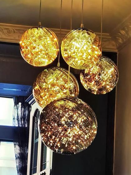 A cluster of golden, fairy-light-filled globes. This pendant chandelier creates a warm and magical ambiance, perfect for a cozy corner or dining area.