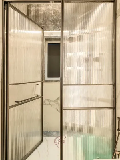A close-up of the fluted glass shower door, which provides privacy while allowing light to pass through, maintaining an open and airy feel.