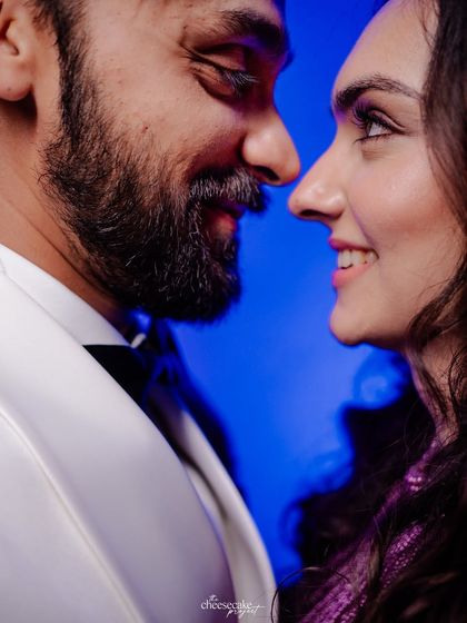 A close-up, intimate portrait of the couple with a vibrant blue background from their Sangeet night.