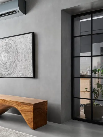 The statement piece in this living room is the sculptural bench I designed, crafted from a single piece of East Indian walnut. Its fluid, curved form contrasts beautifully with the raw, seamless concrete that flows through the space.