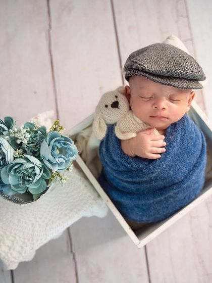 A dapper little gentleman. The newsboy cap and deep blue wrap create a classic, charming look in this box prop setup.