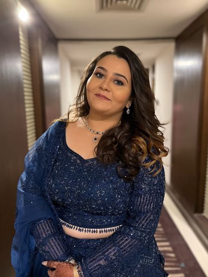 A full view of the glamorous blue lehenga look. The soft curls and defined makeup make her look ready for a night of dancing and celebration.