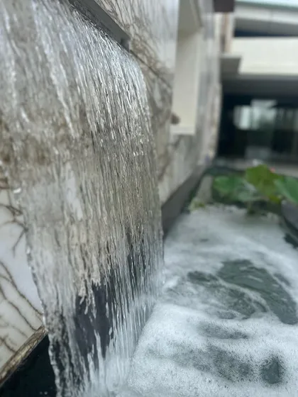 The gentle cascade of a waterfall feature on a marble-clad wall. The sound and sight of moving water add a dynamic yet calming element to our architectural designs.