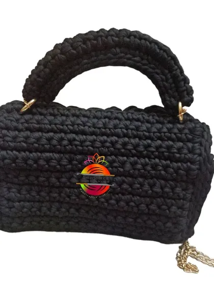 The back view of the black handbag, showing the clean lines and the attachment points for the handle and strap.