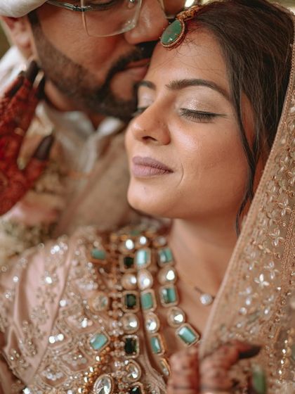 A serene and beautiful portrait of the bride with her eyes closed as the groom kisses her forehead.
