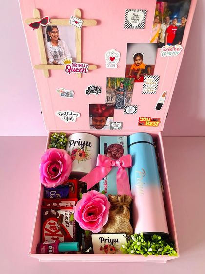 Inside the pink birthday box, a treasure trove of gifts including a personalized mug and flask, chocolates, and a photo collage on the lid.