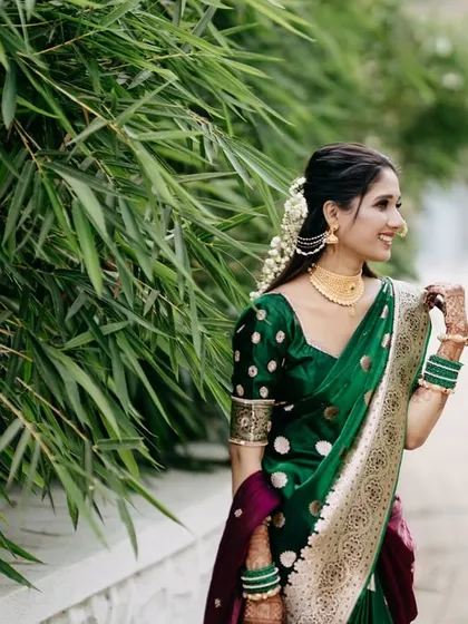A candid and happy portrait of the bride in her green Paithani saree, walking in a garden. Her natural smile and the outdoor setting give this photo a fresh and joyful feel.