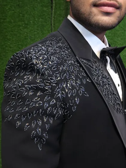 It is all in the details. This close-up shows the hand-embroidered beadwork on one of our signature party wear tuxedos. This level of craftsmanship is what sets our bespoke tailoring apart, adding a touch of luxury and uniqueness to your outfit.
