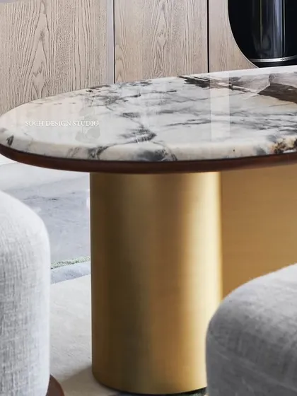 A close-up of the “Ananta” center table, showcasing the beauty of Patagonia Brazilian marble with its scenic, crystal-like patterns. The table is supported by a brass base shaped like an infinity symbol, representing timeless design and enduring quality.